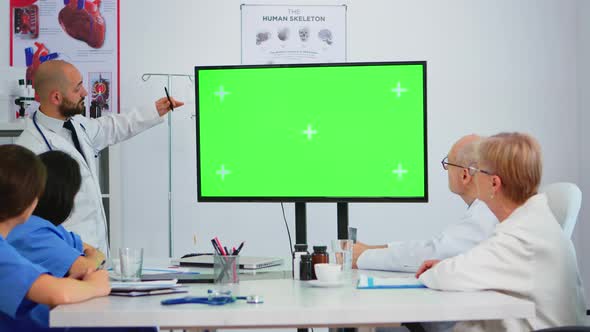 Doctor Explaining Meeting Topics By Previewing on a Green Screen Monitor alt