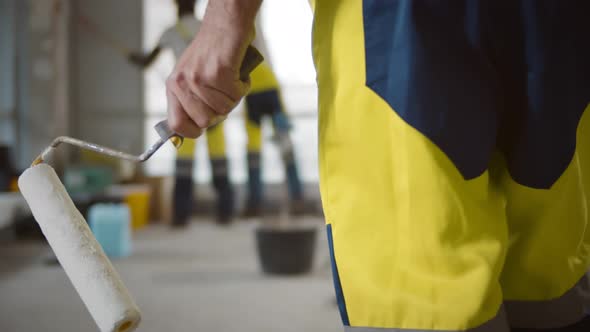 Close Up of Man Builder Holding Roller Brush Redecorating Apartment alt