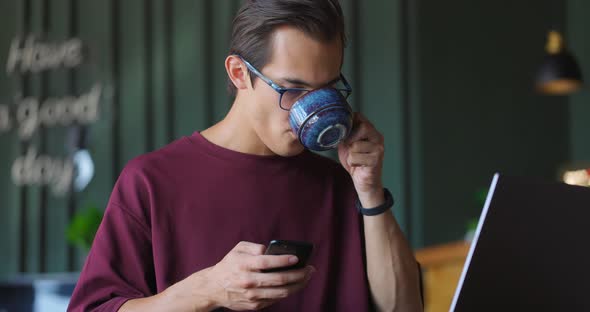 Young Freelancer Using Smartphone and Laptop Computer in Cafe alt