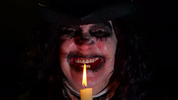 Sinister Woman with Scary Halloween Witch Makeup in Costume Making Voodoo Magic Rituals with Candle alt