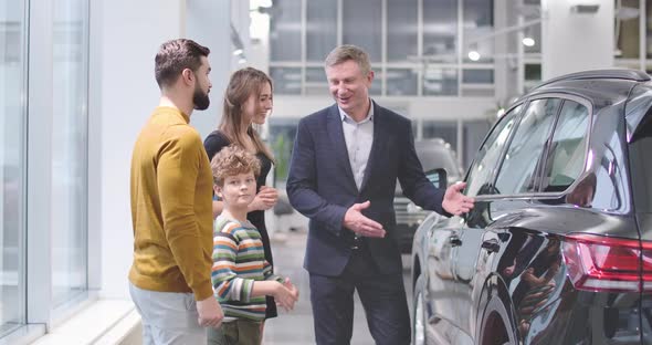 Successful Caucasian Trader Shaking Hands of Male Adult Customer and His Son, Young Beautiful Woman alt