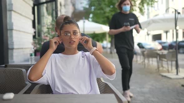 Beautiful Young Woman Sitting in Street Cafe and Listening to Music alt