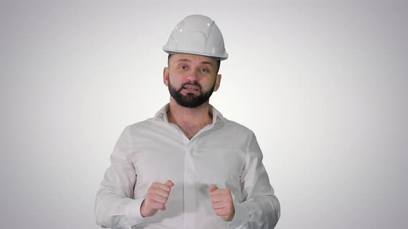 Engineer in a White Helmet Explaining Something To Camera on Gradient Background alt