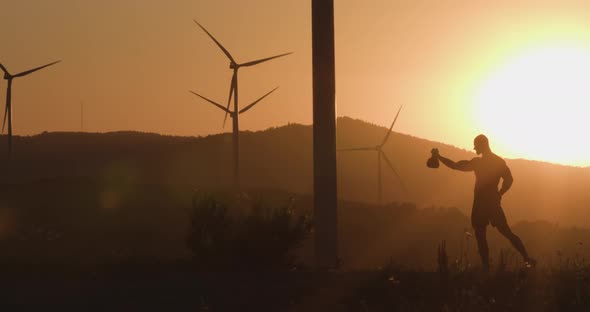 Athlete at Sunset Trains with a Kettlebell. Silhouette Shooting. The Concept of Environmentally alt