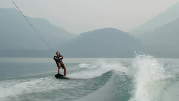 Front view of caucasian young man doing tricks on wakeboard in the city river 4k alt