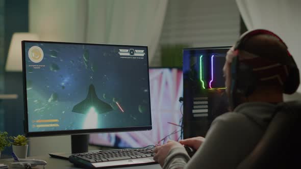 Gamer Player with Headphones and Joypad Performing Space Shooter Video Game alt