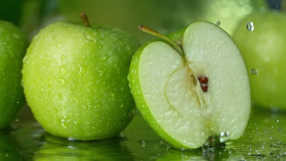 Super Slow Motion Shot of Water Splashing on Fresh Cutted Green Apple at 1000Fps alt