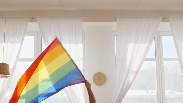 Rainbow LGBT Flag in Hand and Waving on Sunset in Sunny Rays alt