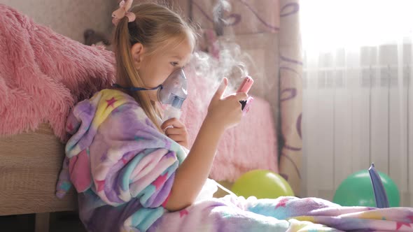Little Girl Holds Inhaler Mask at Home. Sick Kid Breathes Through a Nebulizer. Baby Using Equipment alt