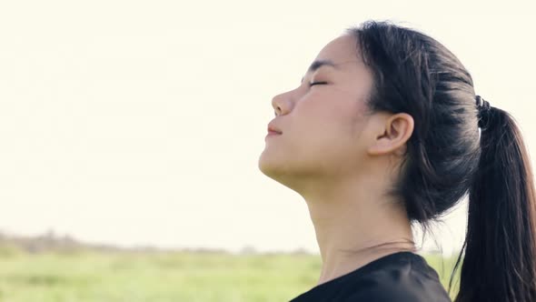 Close-up portrait of young Asian girl relaxed enjoying peaceful sunset. alt