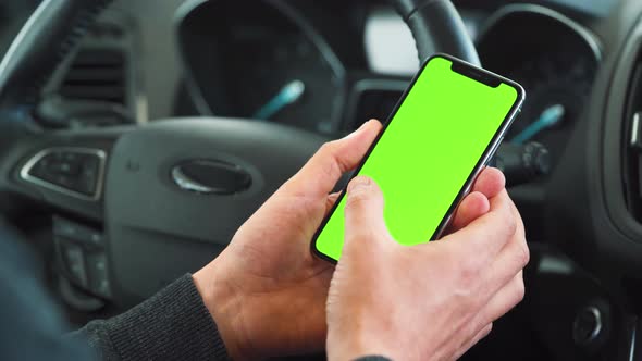 Driver Using a Smartphone Inside the Car. Chromakey Smartphone with Green Screen. Auto Navigation alt