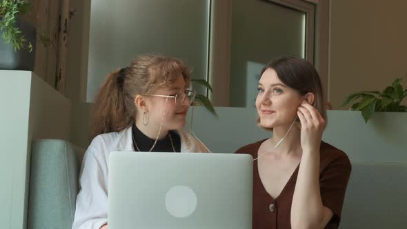 Young Girls Listen to Music Together in a Cafe