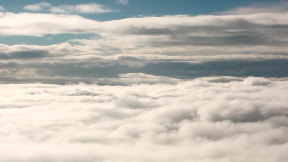 A panning shot of the top of white clouds with the blue sky in view. alt