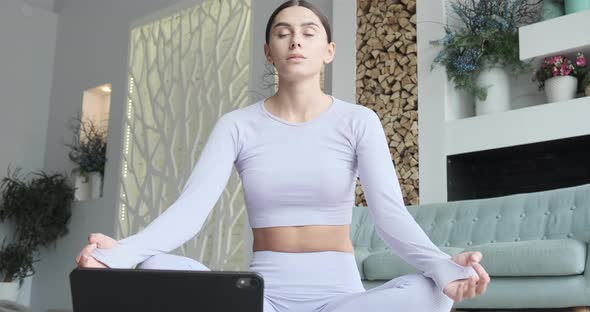 Young Woman Meditating Using Tablet Mobile App for Breathing and Meditation alt