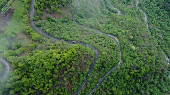 Aerial Shot Of The Winding Mountain Road Between The Trees alt