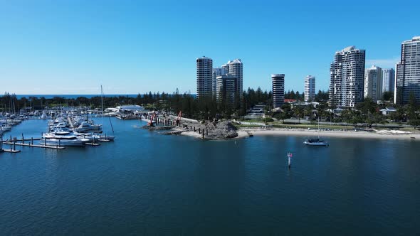 Coastal construction project in a boating marina and harbor next to a towering city skyline. Moving alt