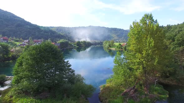 Flying above trees and clear water of Una river in Bosnia alt