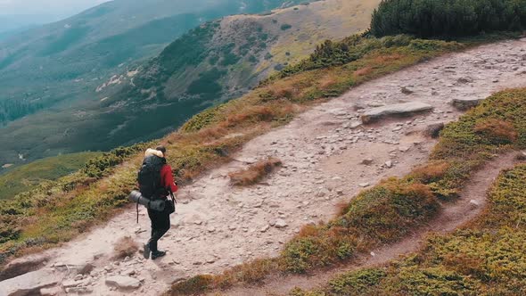 Aerial View of a Traveler Photographer with Backpack Climbing By Mountain Range alt