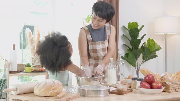 African America family with mother wearing apron thresh flour for cooking and dancing with daughter. alt