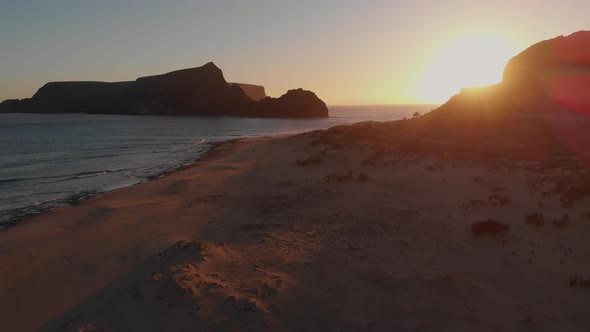 Aerial backwards shot, Calheta beach sunset lights, islet as background alt
