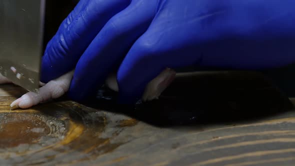 a Korean Chef in Blue Gloves Cuts Off the Nails on Raw Chicken Feet with a Knife alt