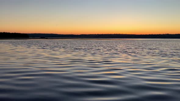 Calm river, slight waves, reflection and glare right before sunrise.