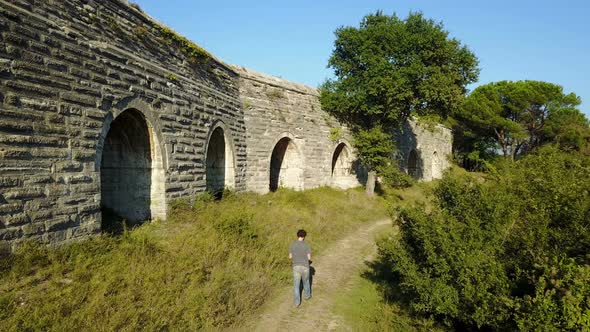 Caucasian Man Walking Near the Ancient Stone Built Aqueduct, Turkey