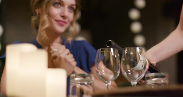 Waiter Pouring Red Wine in Woman Glass While People, Talking,eating,drinking During Romantic Gourmet alt