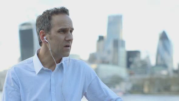 Business man makes a call in the city, in front of the River Thames before leaving