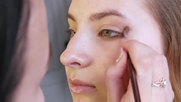 Professional Stylist Makeup Artist Makes Evening Eye Makeup to a Beautiful Girl Model alt