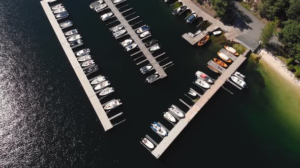 Boats moored in harbour during summer, aerial pull-away reveal alt