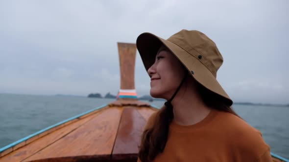 A woman sitting on a long tail boat while traveling in the sea