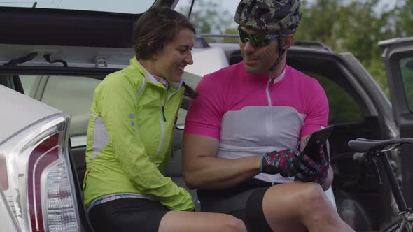 Two cyclists taking break and looking at maps on digital tablet.  Fully released for commercial use.