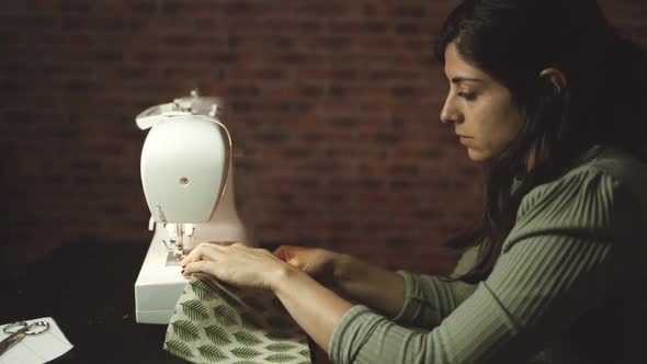 Crop seamstress pulling out thread of sewing machine in atelier alt