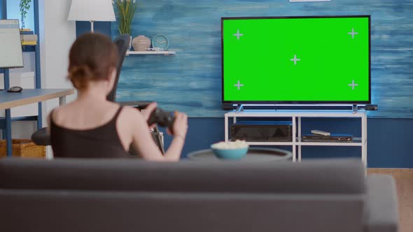 Static Tripod Shot of Gamer Girl Holding Wireless Gamepad Playing Action Console Video Game on Green alt