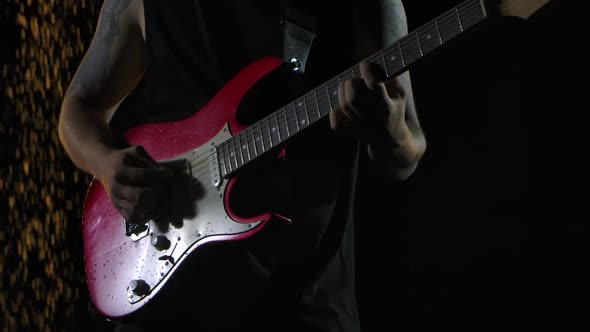 Rock Musician Plays a Red White Electric Guitar in a Dark Studio Against the Background of Falling alt