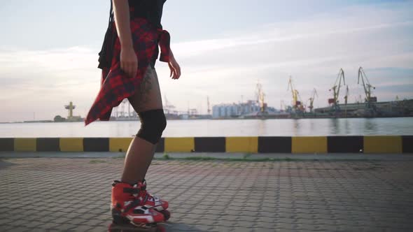 Young Stylish Funky Girl with Green Hair Riding Roller Skates and Dancing Near Sea Port During alt
