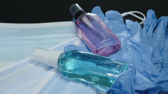 Medical face masks, protective gloves and hand sanitizers are lying on black background alt