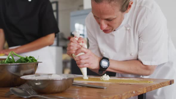 Caucasian female chef teaching diverse group preparing dishes and smiling alt