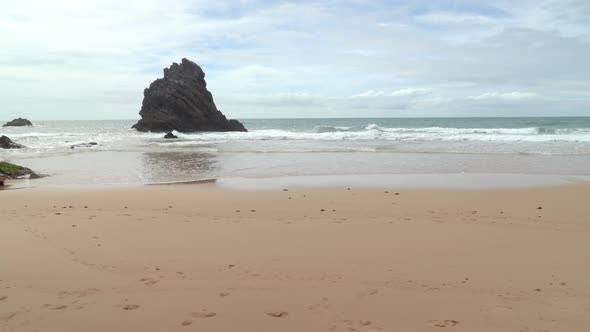 Isolated Black Rock Near the Beach of Gruta da Adraga Mountain Range in Portugal alt