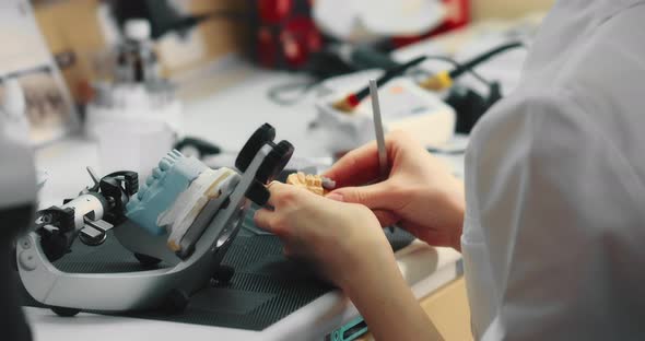 Dental Technician Woman Works with Special Tools with Plaster Models of the Jaw alt
