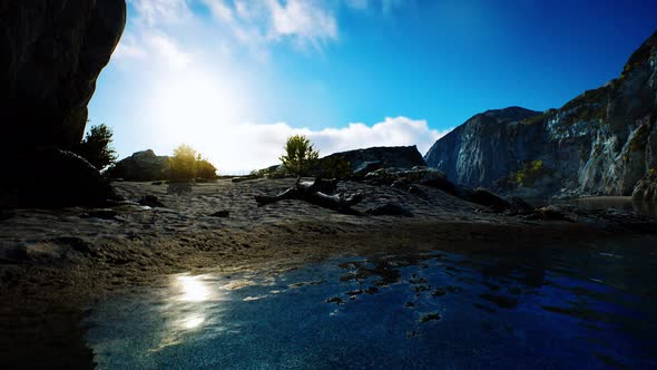 Sandy Beach in Bay Surrounded By Steep Mountains in Sunset alt