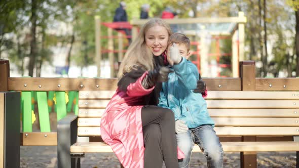 Portrait of Cheerful Woman and Boy Hugging Showing Thumbs Up Smiling Looking at Camera in Sunlight alt
