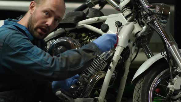 guy mechanic in blue overalls next to a motorcycle