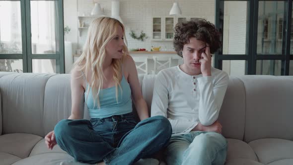 Young Blonde Woman and Boyfriend Quarrelling are Sitting on Couch with Angry Faces Sighing alt