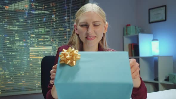 Happy Young Woman Presenting Gift to the Camera and Smiling