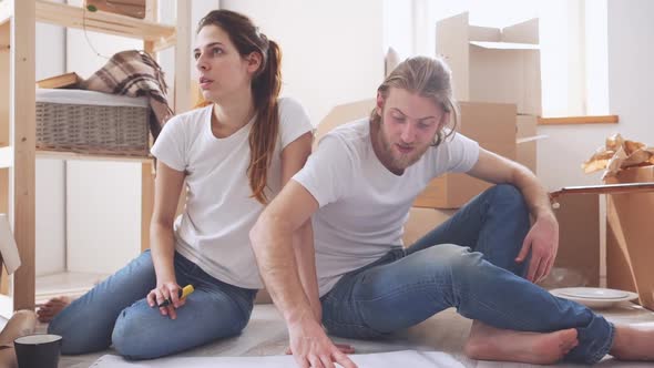 Young Caucasian Pair Planning Furnishings in Their New Flat in Slowmotion alt