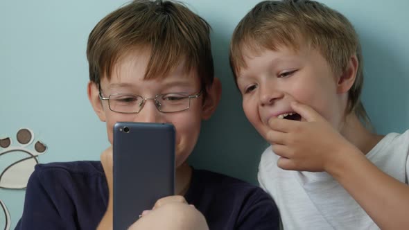 Two Cheerful Boys Using Smartphone Indoors