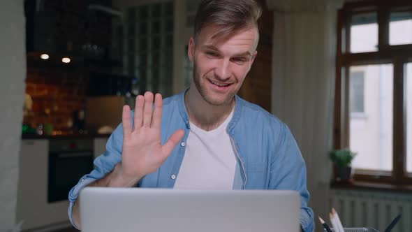 Young American Man is Talking in Video Chat Sitting at Table with Laptop in Apartment Spbas alt