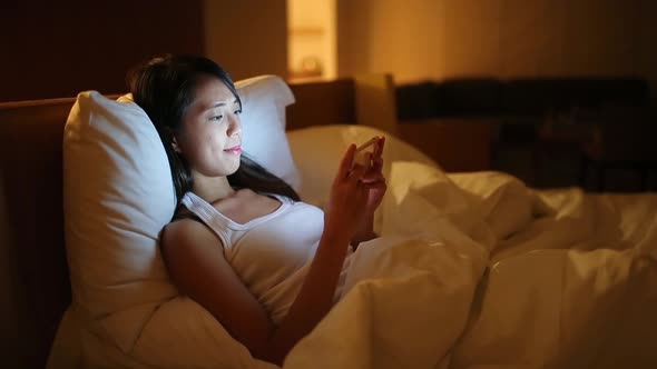 Woman using mobile phone on bed  alt